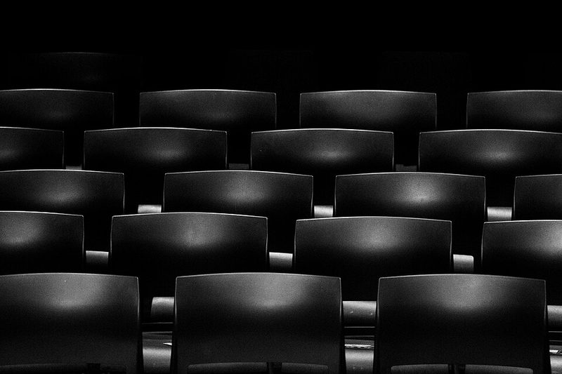 Rows of empty black movie theater seats
