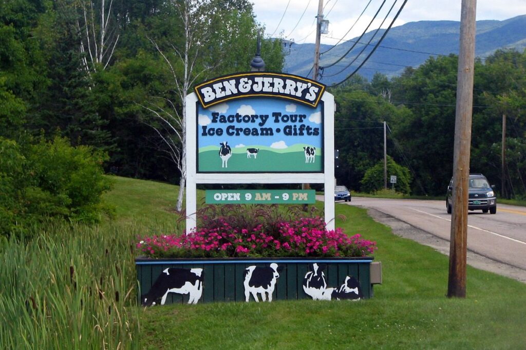 Roadside sign for the Ben & Jerry's factory tour in Waterbury, Vermont, above a planter painted with cows