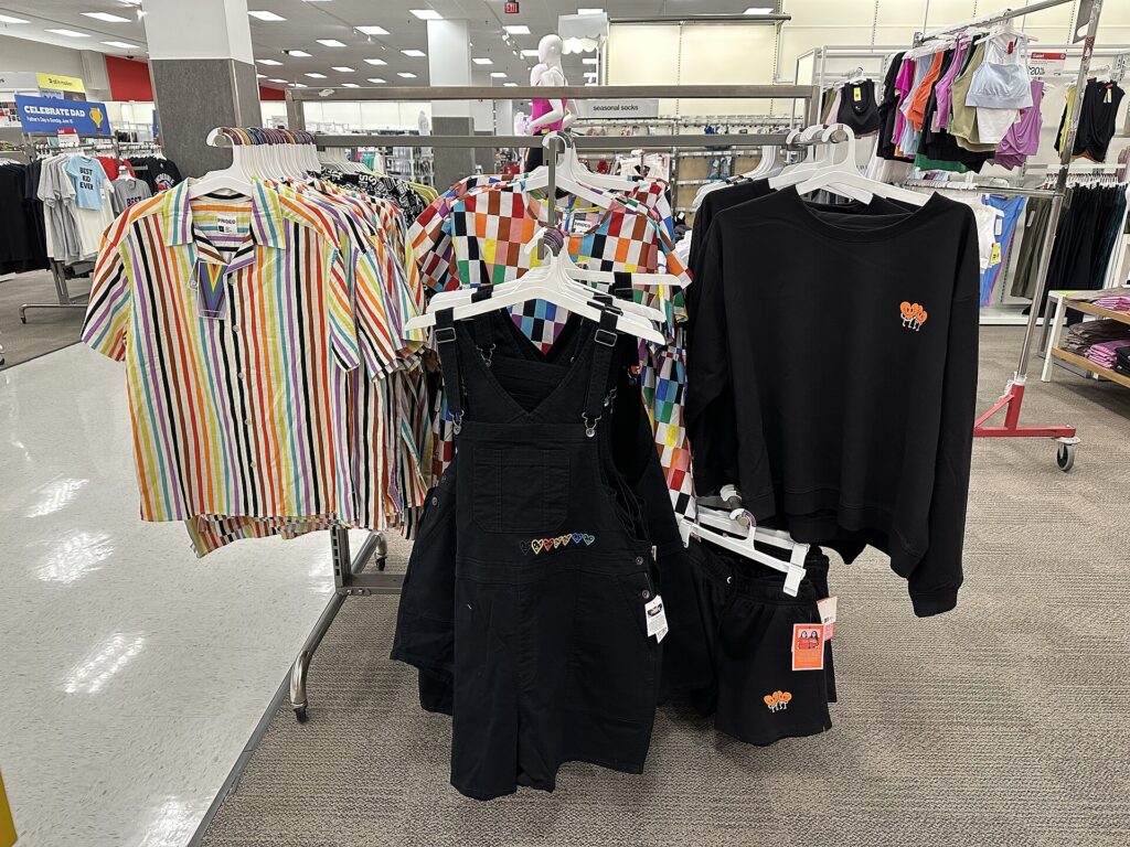 Racks of Pride-themed clothing, including a rainbow-striped shirt and black overalls, in a Target store in Florida in May 2023